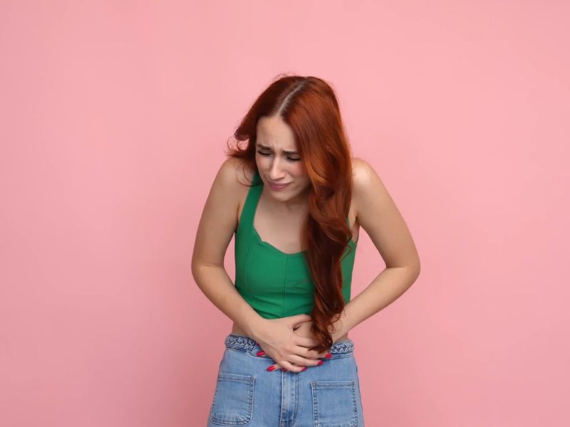 devojka se drži za stomak od bola